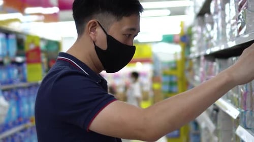 Shopper with Face Mask Selects Supermarket Product