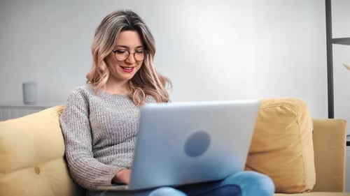 Woman Using Laptop Computer at Home on Sofa