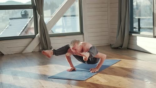 Man Practicing Yoga Arm Balance Inside Bright Room