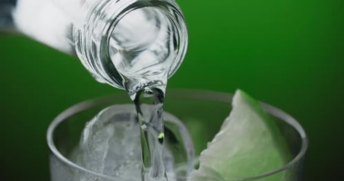 Soda Water is Poured Out From the Bottleneck to the Glass with Cold Drink Lemonade with Limes Ice