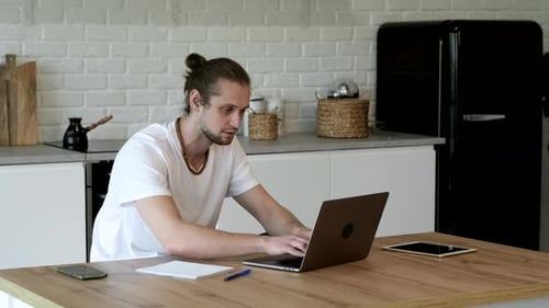 Side view handsome young businessman in eyewear working with computer remotely, sitting