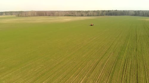 Aerial Photography of a Tractor Spraying Chemicals on a Large Green Field, Agribusiness Concept