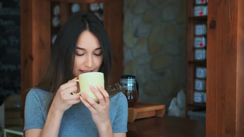 Young Woman Drinking Tea and Relaxing in Cafe