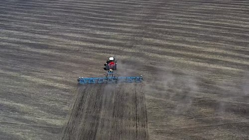 Top View of a Red Tractor Cultivating Brown Earth in Sunny Spring Autumn Weather