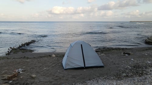 Tent on Sandy Beach Near Ocean Waves