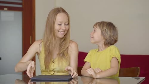 A Young Woman and Her Little Son Sit a Home During Quarantine and Study in the Internet School Using