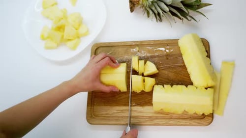 Cutting Fresh Pineapple into Chunks on Cutting Board