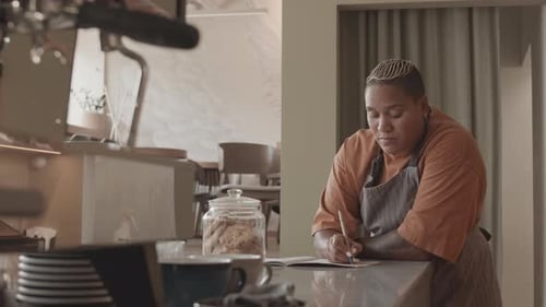 Coworkers Writing Plan Before Shift in Cafe