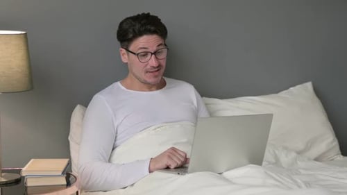 Man in Bed Video Chats on Laptop