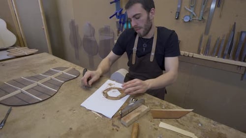 Artesano aplanando pieza de madera con rascador en sala de trabajo