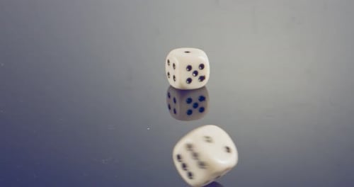 Macro disparo a cámara lenta de dados blancos cayendo y rodando sobre una superficie reflectante