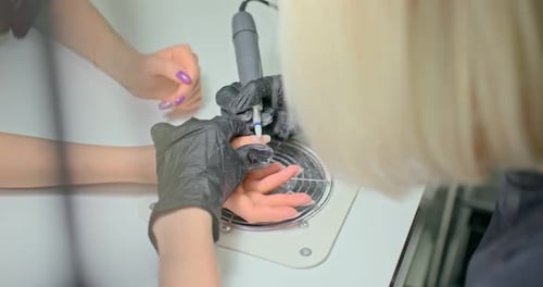 Nail Technician Shaping Nails With Precision Tool