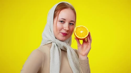 Woman with Headscarf Holding Orange Half