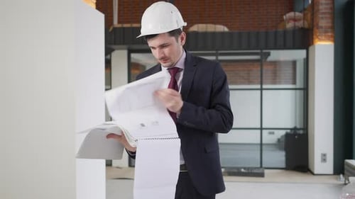 Exhausted Professional Foreman Looking Through Drawings Blueprints Sighing Standing in Premises