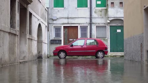 Red Car in the Middle of the Flooded City Street