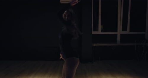 Erstaunliche athletische junge Tänzerin, die im Fitnessstudio unter dem Licht tanzt