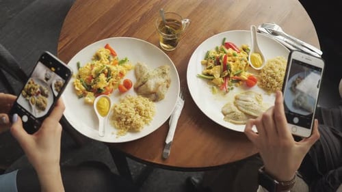 Women Blogger Takes Pictures of Her Food in a Cafe Using Mobile Phone.