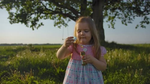 Front View of Little Girl in Blows Soap Bubbles