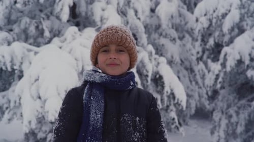 Boy in winter clothes looking at camera and smiling.
