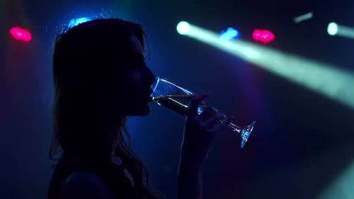 Woman Sipping Champagne in a Dark Nightclub