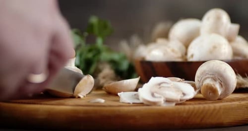Person Slicing Fresh Mushrooms on a Cutting Board