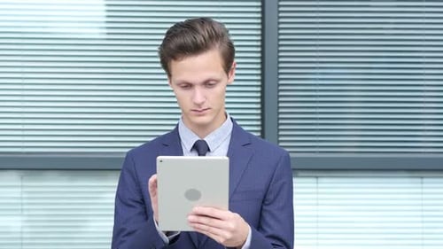 Young Adult Works on Tablet Outside Office