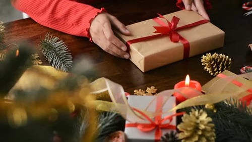 Hands Tying Ribbon on Christmas Gift at Home