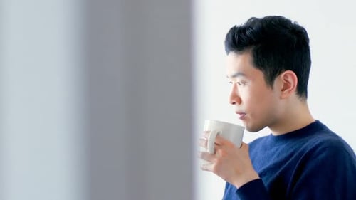 Young Man Using Tablet and Drinking