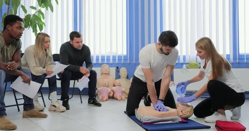 Adults Practicing CPR on Mannequin in Training Class