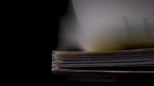 Side View of the Flipping Pages of a Thick Book with English Text