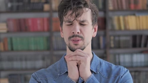 Concerned Man With Clasped Hands In Front Of Bookshelf