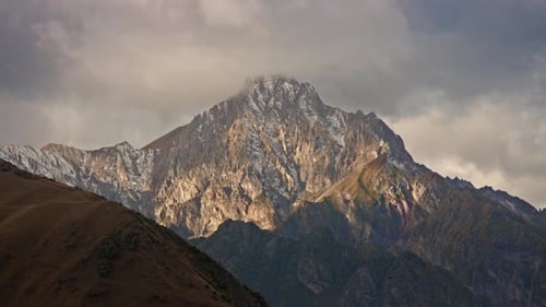 Snowy mountain peak at sunset. Timelapse