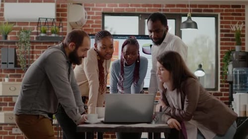 Team Gathers Around Laptop in a Modern Office