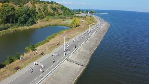 Marathonläufer in weißen T-Shirts laufen entlang der Promenade. Aufnahmen aus der Luftaufnahme