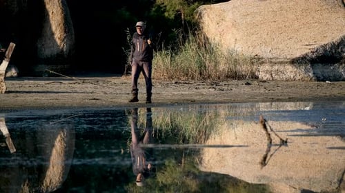 Man Walking on Sandy Beach with Camera