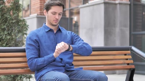 Young Adult Man Checks His Smart Watch