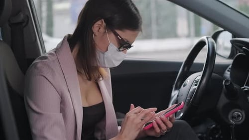 Woman Using Phone in Car with Face Mask