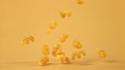 Spiral Pasta Falling on Yellow Background