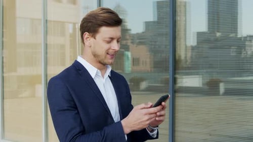 Businessman Typing on Cellphone on Street. Employee Walking for Job on Sidewalk