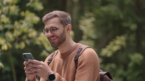 A Man Walks in the Woods and Writes a Message on His Mobile Phone