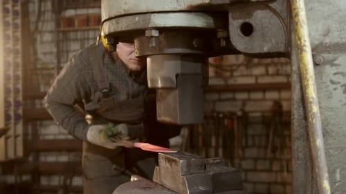 Man Forging Metal with Heavy Industrial Press