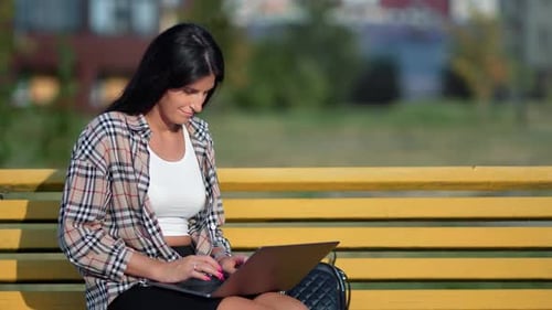 Confident Casual Freelancer Brunette Woman Working Remotely Use Laptop Sitting at Summer Park Bench