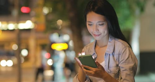 Woman using mobile phone at night
