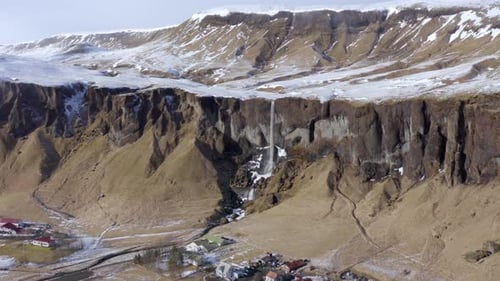 Kleiner und schöner Wasserfall auf einem schneebedeckten Felsvorsprung im Winter