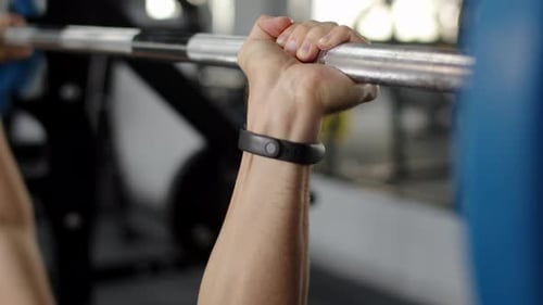 Closeup of Hands of Male Athlete Conducting Workout Lifting Barbell in Gym