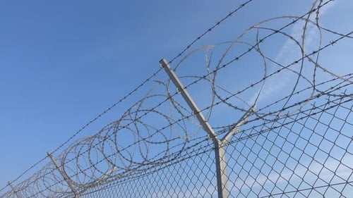 Chain Link Fence with Barbed Wire Under Blue Sky