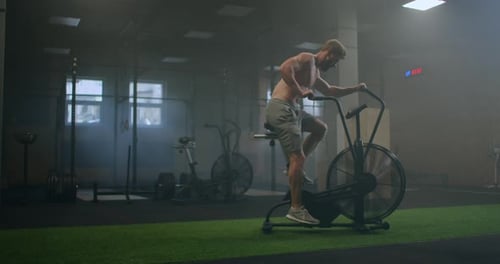 a Man Dominates an Aerobics Ride in the Gym in Slow Motion. Cardio Training on a Stationary Bike