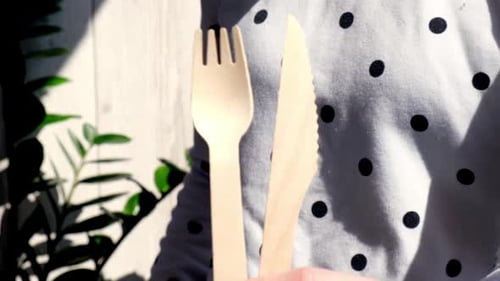 Person holding wooden knife and fork