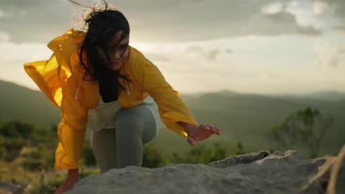 The Girl Climbs the Rocks to the Top of the Mountain