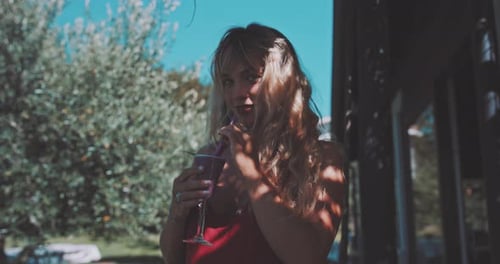 Gorgeous blonde young woman drinking a beverage from the straw and looking in the camera